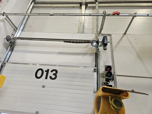 Albero con molla a torsione sopra una porta sezionale industriale – riparazione serrande a Padova